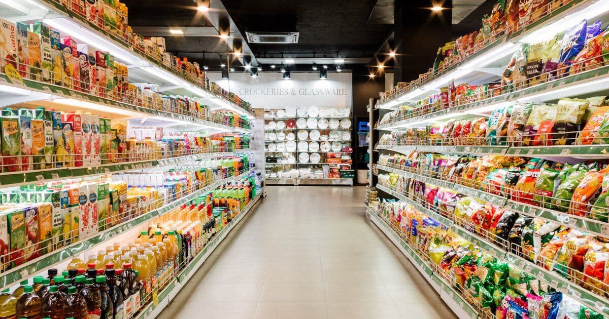 A wide aisle of packaged groceries inside Khulshi Mart